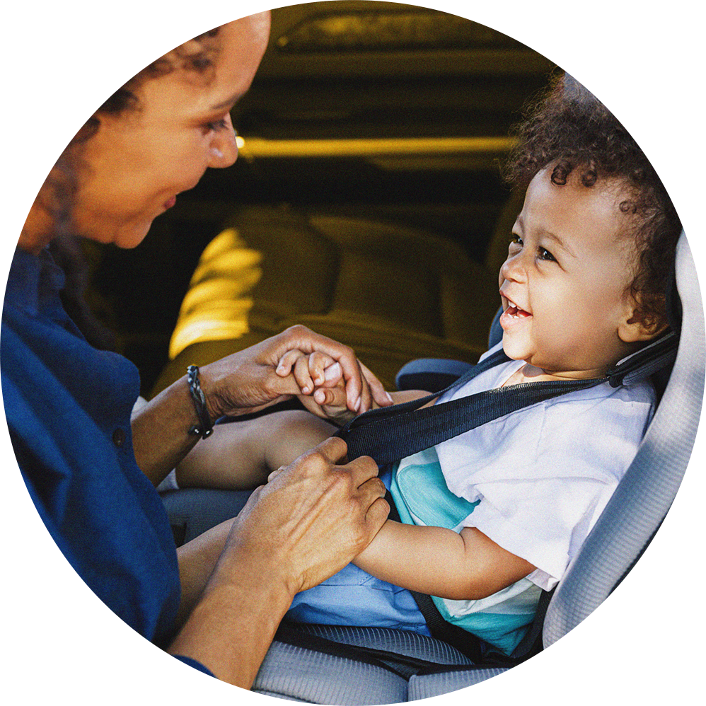 mom helping young child in car seat